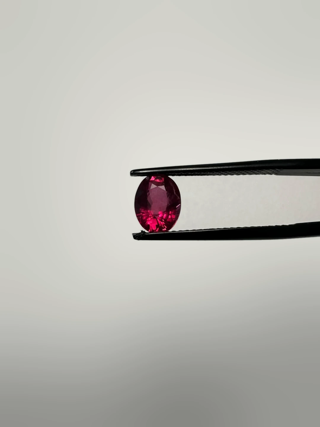 Oval-cut ruby held in tweezers